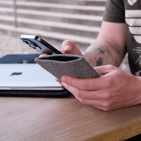 Stilvolle Handytasche für das Samsung Galaxy A37 aus hellgrauem Filz, die vor einem Laptop im Hintergrund gehalten wird.