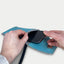 Person, die ein Motorola Razr 60 ultra in eine stilvolle hellgraue und blaue Filztasche mit Schulterriemen steckt.